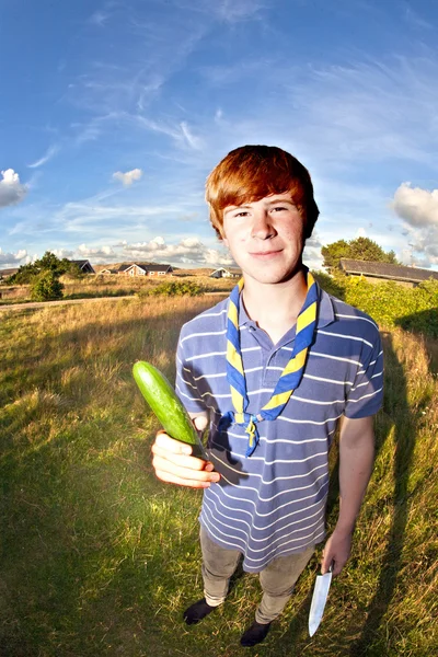 Jongen met mes en komkommer — Stockfoto