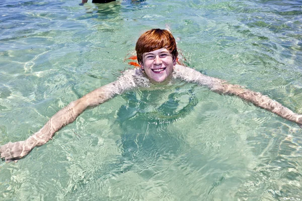 Κομψός αγόρι αγαπάει κολύμβησης στον ωκεανό σαφές — Φωτογραφία Αρχείου
