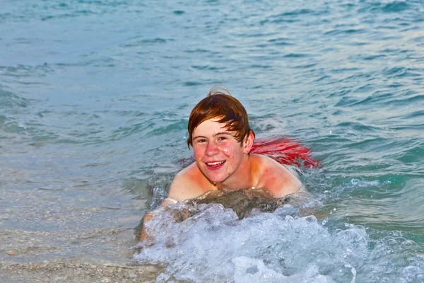 Мальчик, лежащий на пляже, наслаждается волнами океана — стоковое фото
