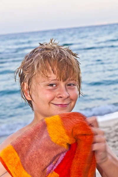 Умный улыбающийся мальчик на пляже во второй половине дня после купания — стоковое фото