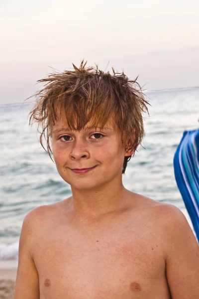 Niño sonriente inteligente en la playa al final de la tarde después de nadar —  Fotos de Stock