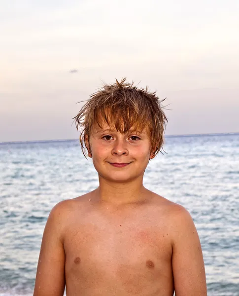 Slimme lachende jongen op het strand in de late namiddag na het zwemmen — Stockfoto