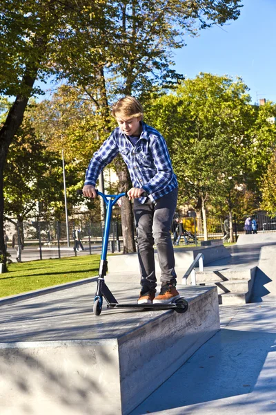 Мальчик прыгает на скутере в скейт-парке — стоковое фото