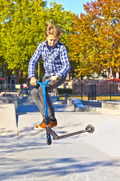 Мальчик прыгает на скутере в скейт-парке — стоковое фото