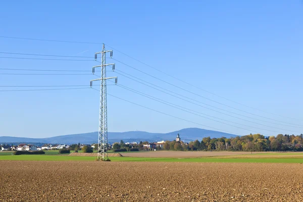Torre eléctrica en campo bajo cielo azul —  Fotos de Stock