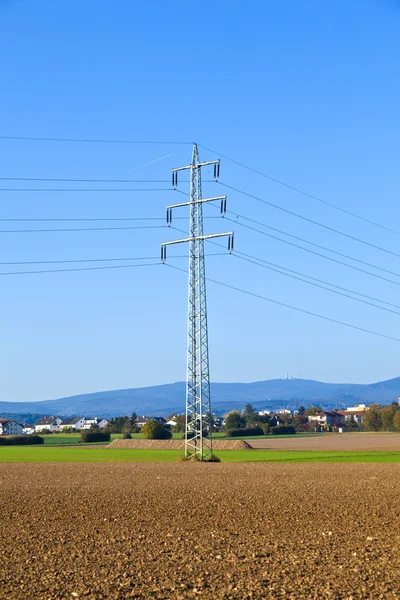 Torre elétrica no campo sob o céu azul — Fotografia de Stock