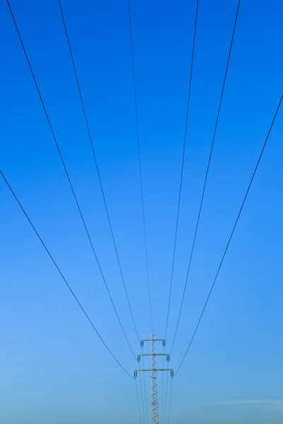 Електрична вежа в полі під блакитним небом — стокове фото