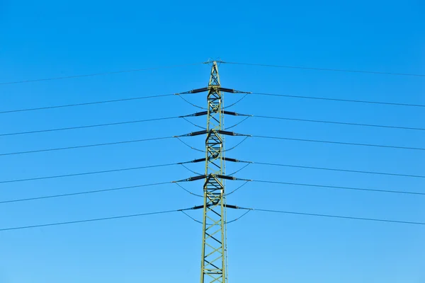 Torre elettrica in campo sotto il cielo blu — Foto Stock