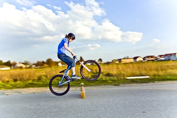 Jovem pulando com sua bicicleta suja sobre uma barreira no stree — Fotografia de Stock