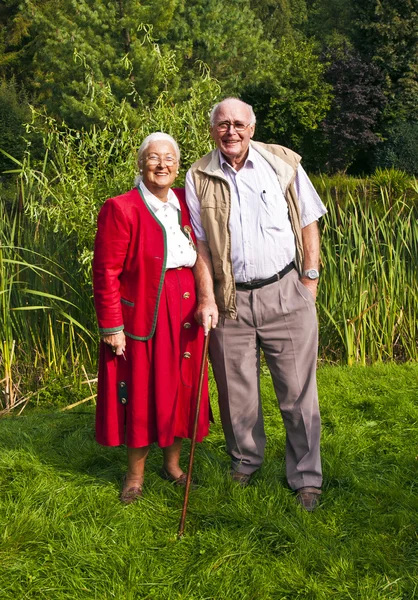 Starší pár stojí ruku v ruce v jejich zahradě — Stock fotografie
