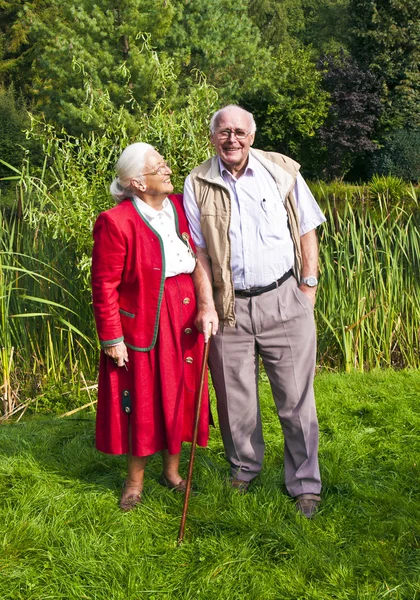 Para starszych stojący ręka w rękę w ich ogrodzie — Zdjęcie stockowe