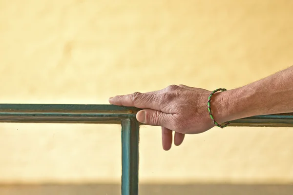 Χέρι με βραχιόλι κλίνει σχετικά με ένα πλαίσιο παραθύρου — Φωτογραφία Αρχείου