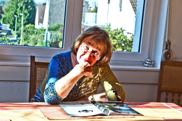 Oudere aantrekkelijke vrouw thuis in een tijdschrift lezen — Stockfoto
