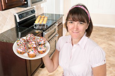 Homemaker holding plate of cupcakes clipart