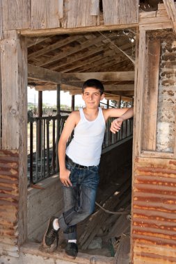 Boy standing at old barn clipart