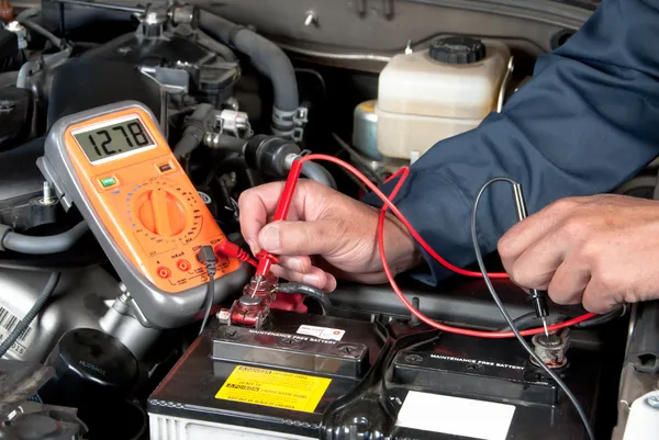 Auto mecânico verificando a tensão da bateria do carro — Fotografia de Stock