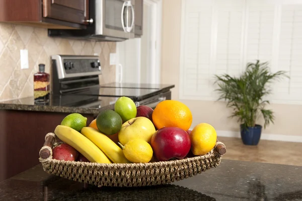 Basket of fresh fruit in modern kitchen — Stock Photo, Image