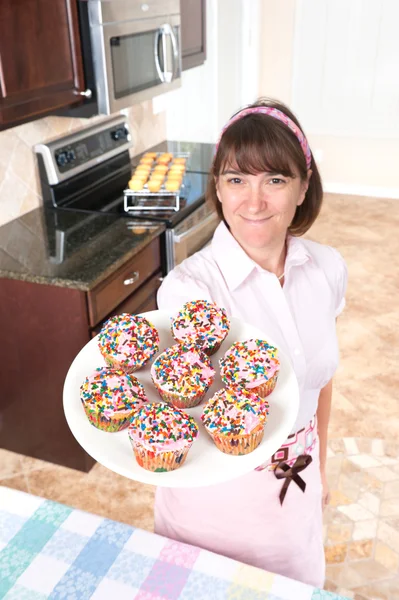 Hausfrau hält Teller mit Cupcakes — Stockfoto
