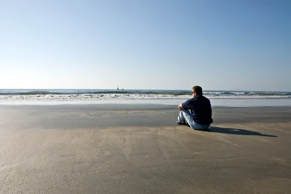 Человек один на пляже — стоковое фото