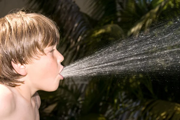 Мальчик плюет водой — стоковое фото