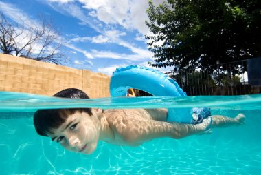Boy swimming in pool with float ring clipart