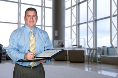 Businessman taking notes in lobby clipart