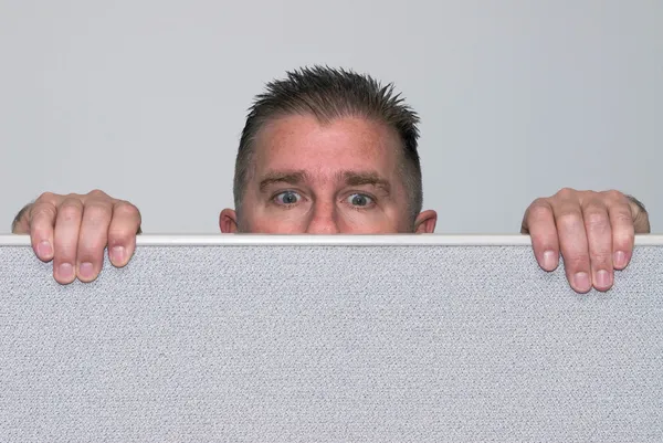 Человек, заглядывающий в офисную кабинку — стоковое фото