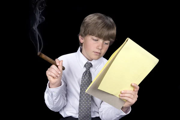 Мальчик в деловом костюме курит сигары и читает — стоковое фото