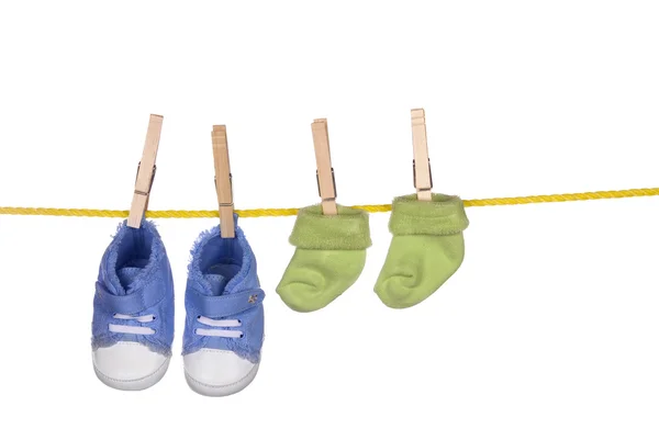 Детская обувь и сочка висят на веревке для белья — стоковое фото