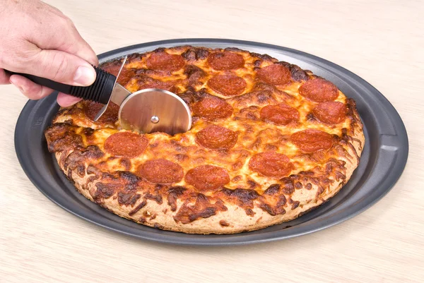 Skivning en pepperoni pizza — Stockfoto