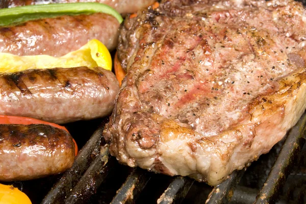 Biefstuk en braadworst op barbecue — Stockfoto