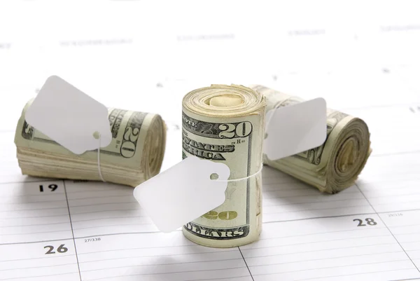 Money rolls on calendar — Stock Photo, Image