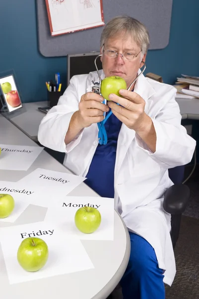 Läkaren undersöker ett äpple — Stockfoto