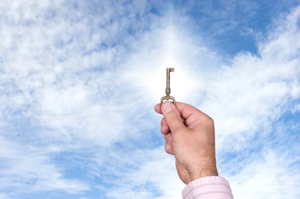 Homem segurando a chave contra o céu brilhante — Fotografia de Stock