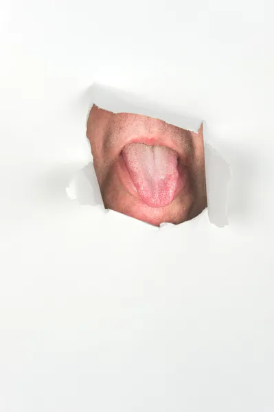 Man sticker ut tungan genom papper — Stockfoto