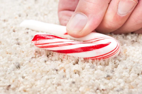 Candy cane stuck to carpet — Stock Photo, Image