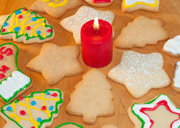 Kırmızı mum çevreleyen renkli Noel kurabiyeleri — Stok fotoğraf