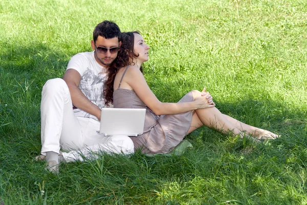 Hombre joven con portátil y chica en la hierba verde — Foto de Stock
