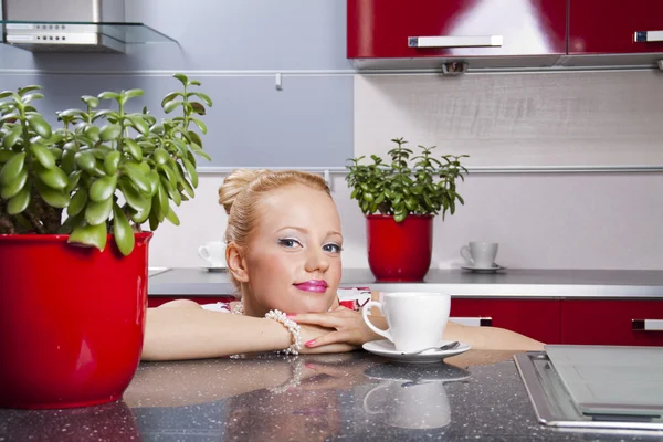 Young beautiful women sitting in kitchen drinking coffee Stock Picture