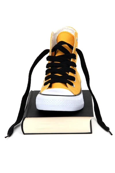 Жовтий кросівок на чорній книзі — стокове фото