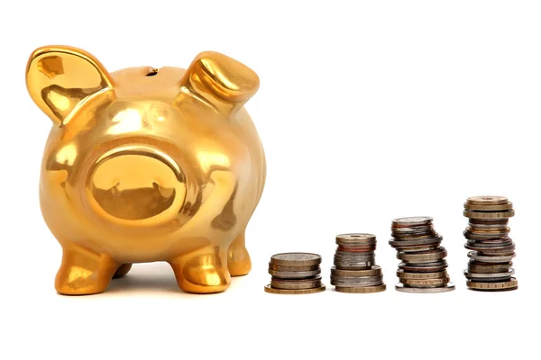 Gouden piggy bank en stapels munten — Stockfoto