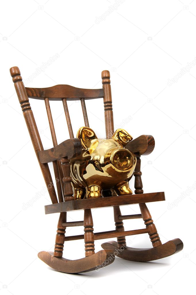 Old wooden rocking chair and golden piggy bank on white