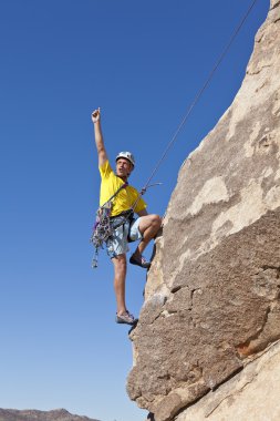 Male rock climber clings to a cliff. clipart