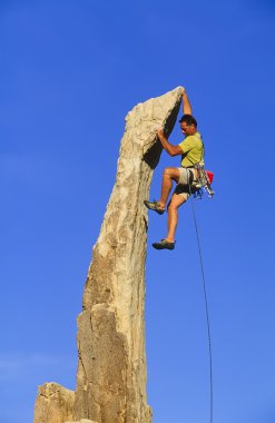 Climber clinging to a cliff. clipart