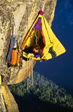 Rock climber bivouaced in a portaledge. clipart