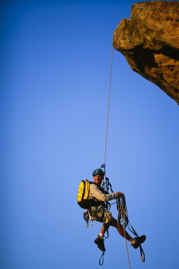 Rock climber rappelling. clipart