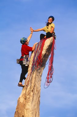 Rock climbing team reaching the summit. clipart