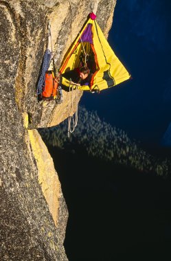 Rock climber bivouaced in a portaledge. clipart