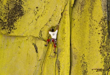 Male climber working his way up a steep crack. clipart