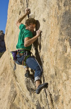 Climber clinging to a cliff. clipart